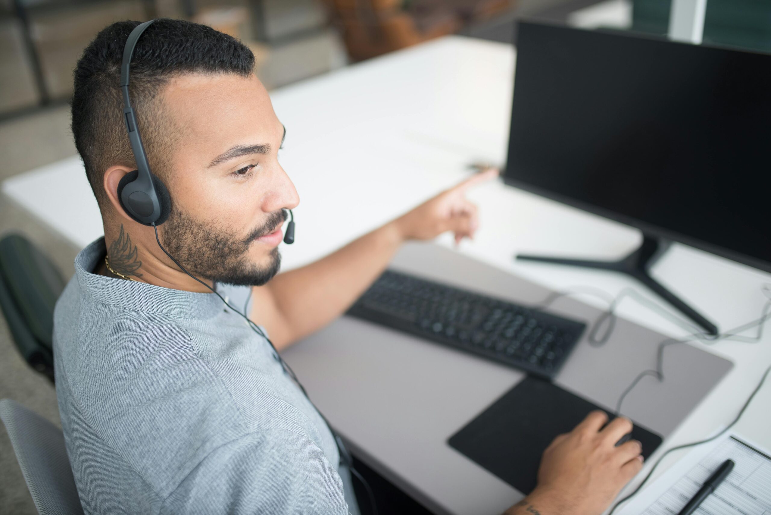 Customer service agent using a computer and headset within a modern office setting.